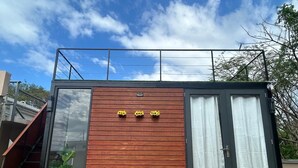 Un edificio moderno y compacto con fachada de madera, ventanas grandes y un pequeño balcón.