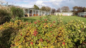 A modern building with a covered outdoor area, surrounded by well-maintained lawns and flowering plants. - 31 Seaward Crest (Norwich)