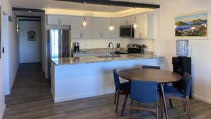 A modern kitchen with a central island, stainless steel appliances, and pendant lighting. - VIEWS & MORE VIEWS!  Cowpet Bay East, water front condo, steps from beach.  (St Thomas)