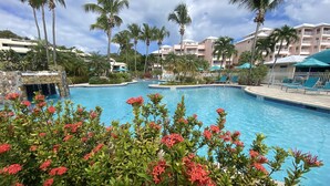 A swimming pool with a stone waterfall feature, surrounded by lush greenery and palm trees. - VIEWS & MORE VIEWS!  Cowpet Bay East, water front condo, steps from beach.  (St Thomas)