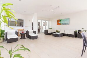 A spacious living area with wicker furniture, a ceiling fan, and a large window.