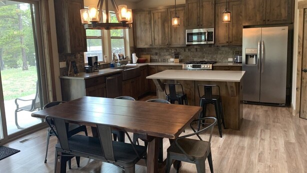 A modern kitchen with wooden cabinets, a central island, and stainless steel appliances. - Explore Natures Beauty and Stay at Home in the Heart of Oregon's Wonderland (Bend)