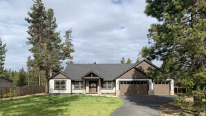 A two-story house with a front driveway, a garage, and a well-maintained lawn. - Explore Natures Beauty and Stay at Home in the Heart of Oregon's Wonderland (Bend)