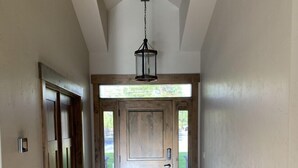 A hallway with wooden flooring, a grey rug, and a wooden door with glass panels. - Explore Natures Beauty and Stay at Home in the Heart of Oregon's Wonderland (Bend)