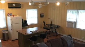 Ein kompakter Wohnbereich mit einer Küchenzeile, einem Essbereich und einer Sitzecke mit einer Couch.