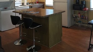 Eine kompakte Küche mit Kochinsel, Barhocker, Herd, Kühlschrank und Mikrowelle.