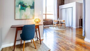 A modern living room with a wooden desk, a blue chair, and a large abstract painting on the wall. - Modern Old City Loft - Downtown Knoxville (Knoxville)