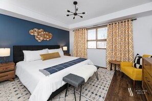 Ein modernes Hotelzimmer mit einem großen Bett, einem Nachttisch, einem Sessel und einer dekorativen Wandgestaltung.