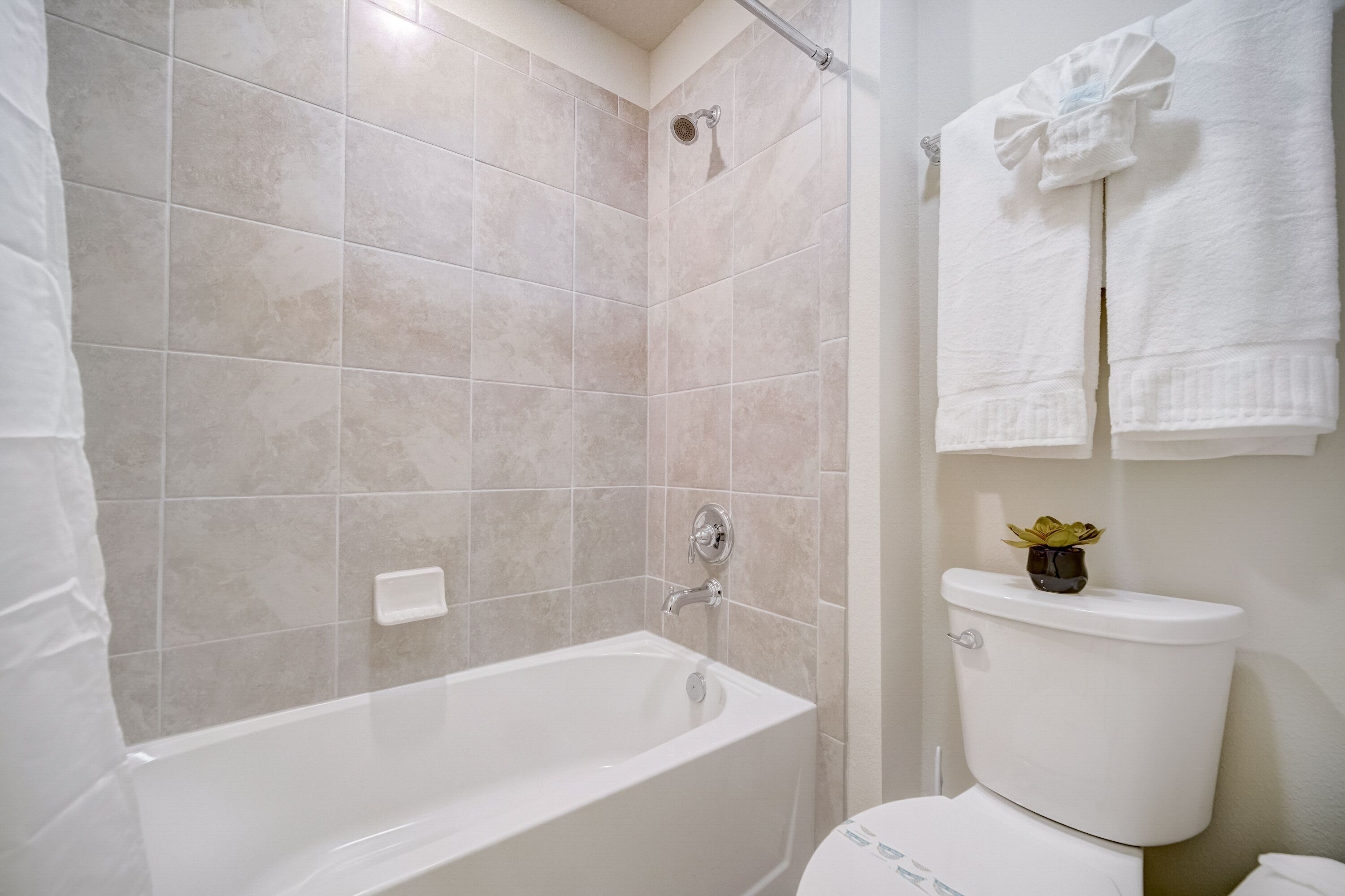 A bathroom with a bathtub, toilet, and a towel rack with towels.
