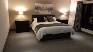 Cozy bedroom with a large bed, bedside tables, and a framed picture above.