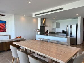 Una cucina moderna con isola centrale, elettrodomestici in acciaio inossidabile e zona pranzo con tavolo e sedie in legno.