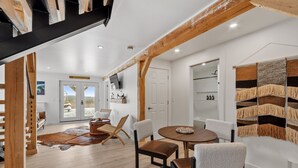 A spacious room with a wooden ceiling, a round dining table with chairs, a large woven rug, and a view of the outdoors through glass doors. - EPIC VIEWS - Pond - Crooked River 14 ACRES - SECLUDED (Harrison)