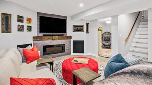 Un salon moderne avec une cheminée, un téléviseur à écran plat et un escalier.