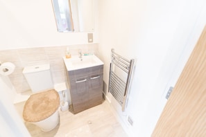 A small bathroom with a toilet, sink, and mirror. - Modern Apartment in Salford, Manchester, UK (Salford)