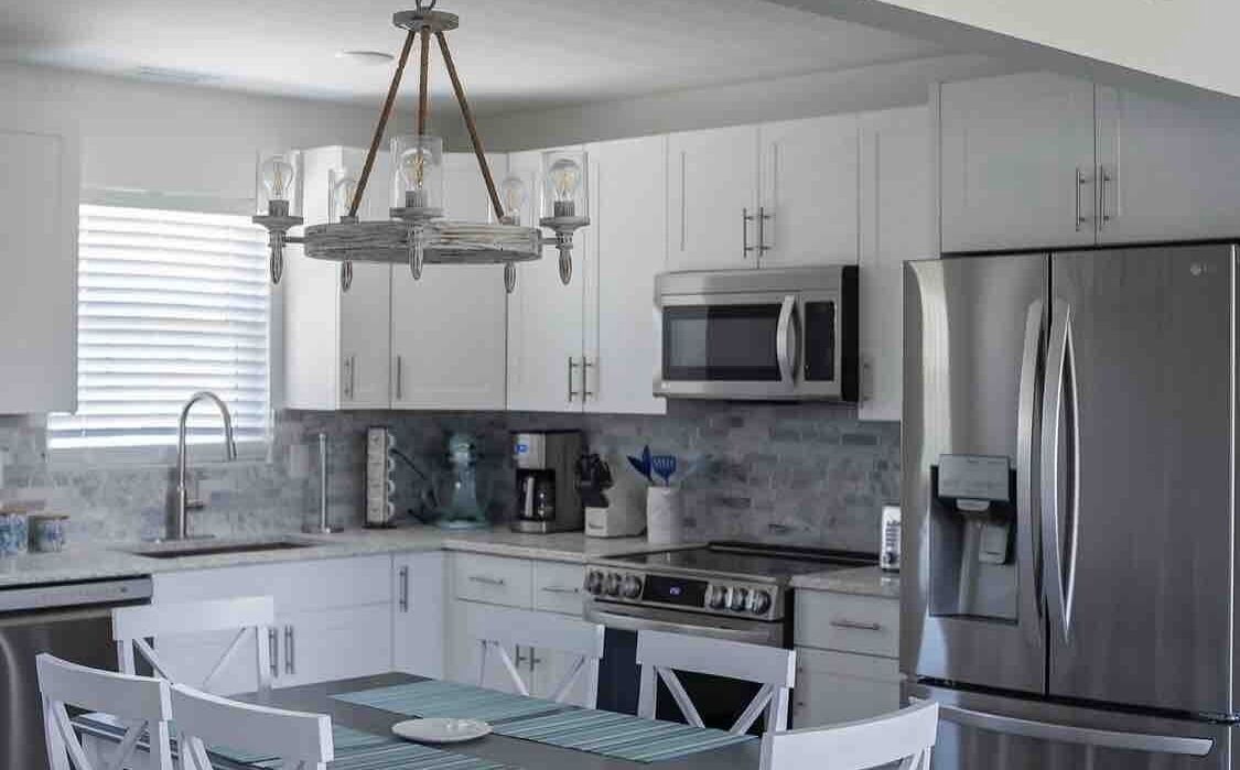 A modern kitchen with white cabinets, stainless steel appliances, and a central island with seating.