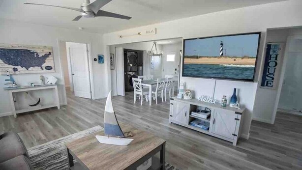 Una sala de estar moderna con un modelo de velero, un televisor de pantalla plana y vista al océano.