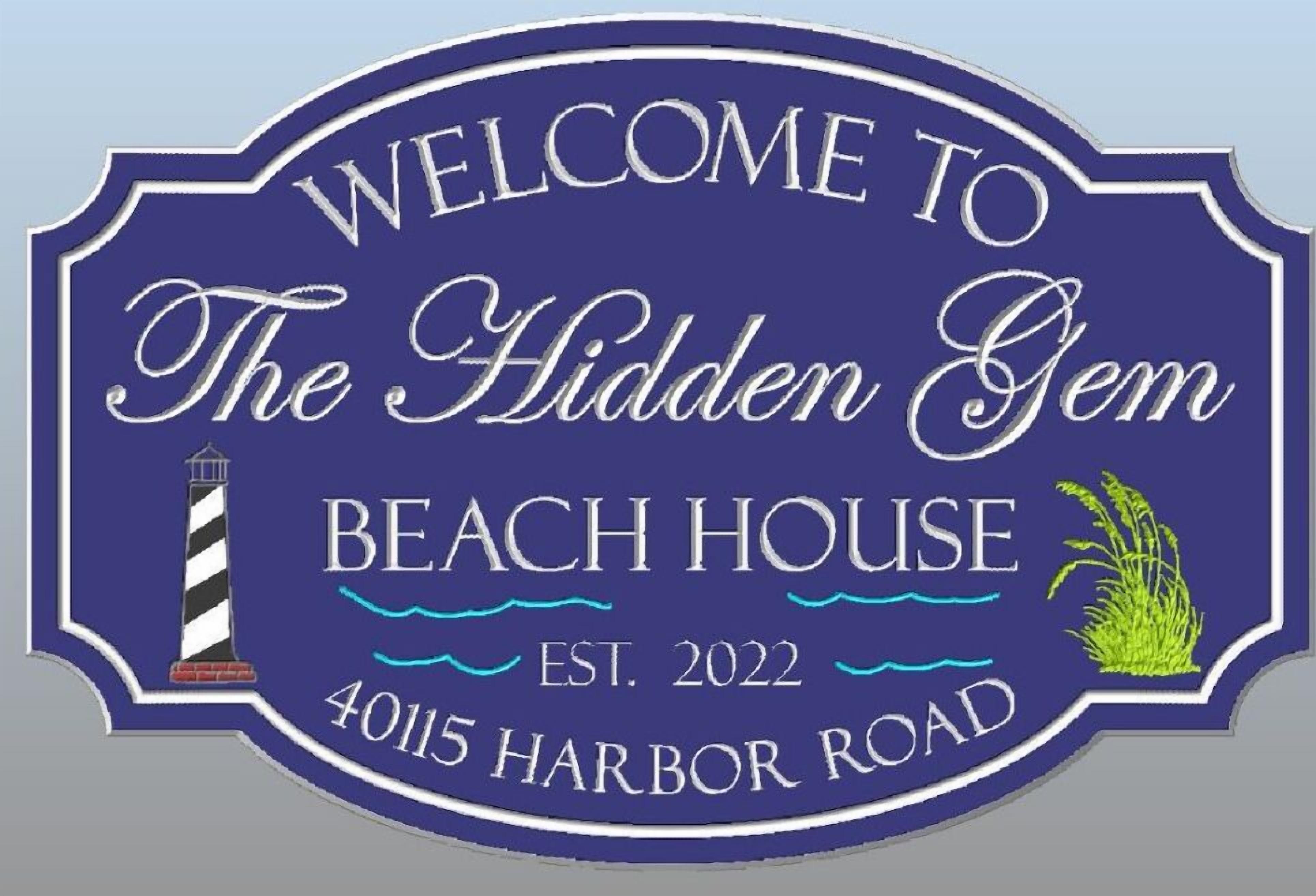 A welcome sign for The Hidden Gem Beach House, established in 2022, located at 40115 Harbor Road.