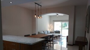 A modern kitchen with a central island, dining area with a sofa, and a view of the outdoors. - C-Signature Luxory Condo 122, Green Bay 3, El tigre Nuevo Vallarta (Nuevo Vallarta)