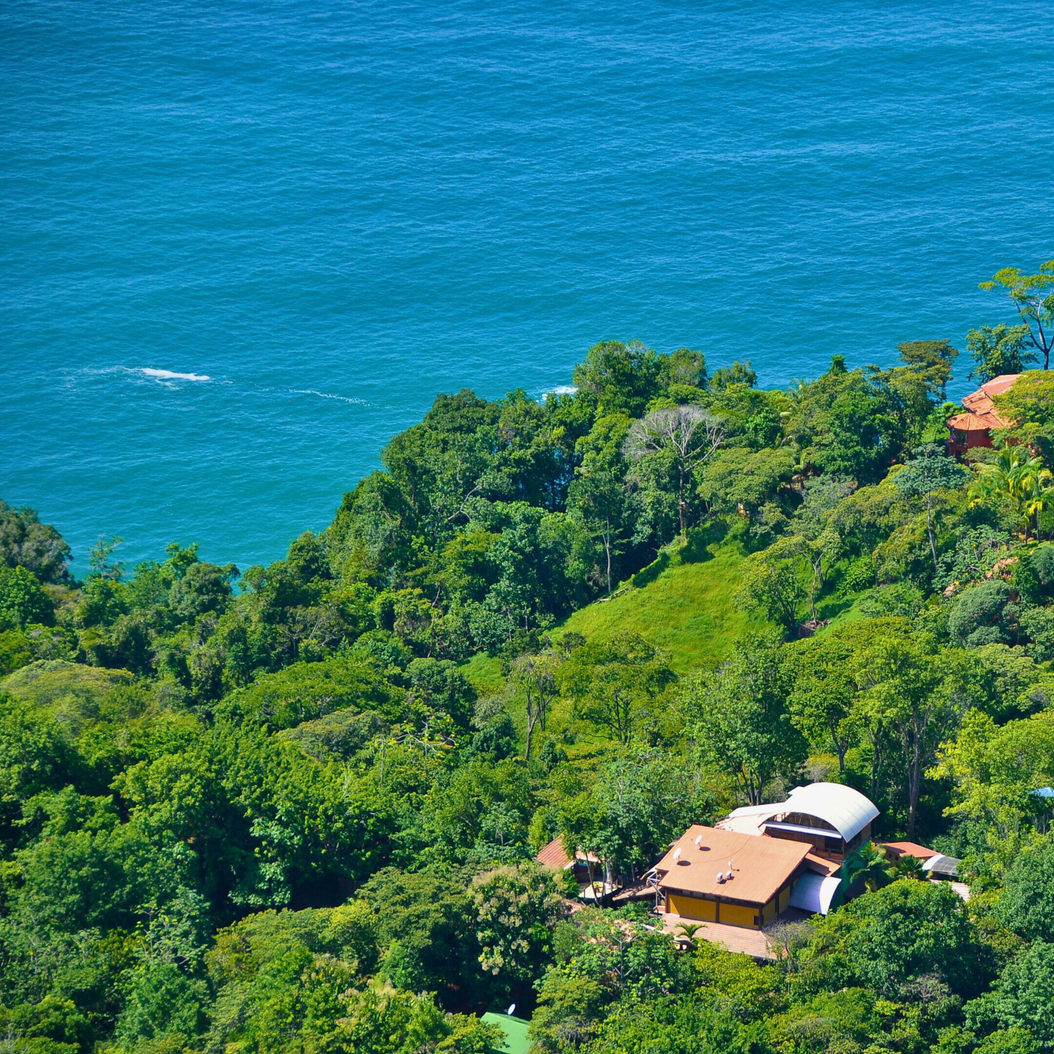 A coastal property with lush greenery and a view of the ocean.