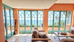 Una habitación con un ventanal grande, un sofá, una mesita y un objeto decorativo.