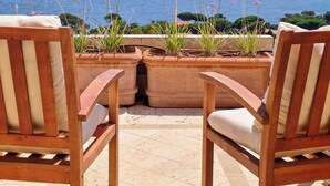Two wooden chairs with cushions, a tiled floor, and potted plants with flowers. - Villa 10 people, pool, sea view, beach on foot (Sainte-Maxime)