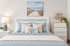 Une chambre à coucher avec un lit, une table de chevet, une lampe, un tableau et des poissons décoratifs.