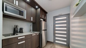 A modern kitchen with dark wood cabinets, a stainless steel refrigerator, a microwave, and a sink. - Beachfront Cozy Loft  Walk 2 Eat Isla Verde Beach (Carolina)