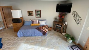 Une chambre à coucher comprenant un lit, un téléviseur à écran plat, un four à micro-ondes, un petit meuble et une cheminée.