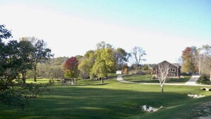 Une zone verdoyante bien entretenue, avec quelques arbres et un petit bâtiment visible au loin.