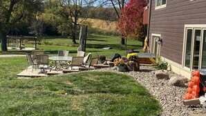 Un jardin à l’arrière d’une maison, aménagé avec une terrasse, du mobilier d’extérieur et une maison dont le revêtement extérieur est de couleur foncée.