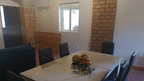 Un coin repas avec une table en bois, des chaises noires et un centre de table composé de fruits.