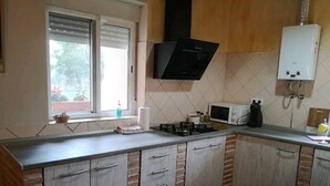 Une cuisine avec une fenêtre, un four à micro-ondes, une cuisinière à gaz et des placards.