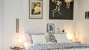A bedroom with a large bed, a bedside table with a lamp, a wall-mounted artwork, and a hanging light fixture. - Sweet modern spot close to city center (Zagreb)