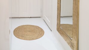 A hallway with a white door, a wooden-framed mirror, and a woven rug. - Sweet modern spot close to city center (Zagreb)
