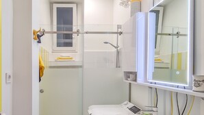 A modern bathroom with a glass shower enclosure, a white sink, and a large mirror. - Sweet modern spot close to city center (Zagreb)