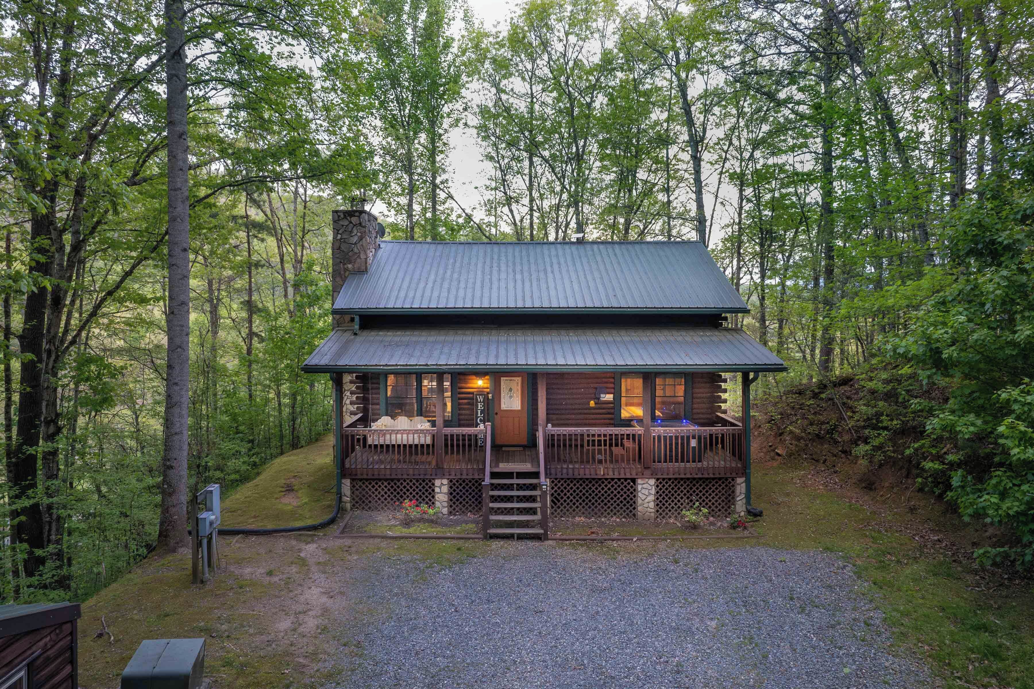 A cabin with a porch, wooden deck, and a stone chimney.