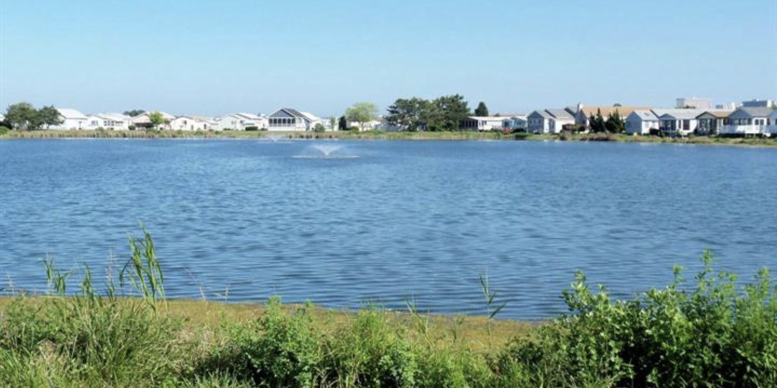 Un lago con casas al fondo.