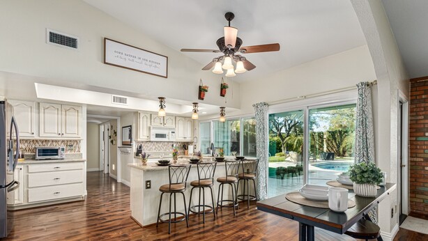 A spacious kitchen with a central island, bar stools, and a ceiling fan. - Resort Backyard w/Private Pool- Spacious Home close to Stadium & Spring Training (Glendale)