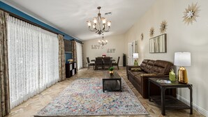 A living room with a chandelier, a sofa, a coffee table, and a rug. - Resort Backyard w/Private Pool- Spacious Home close to Stadium & Spring Training (Glendale)