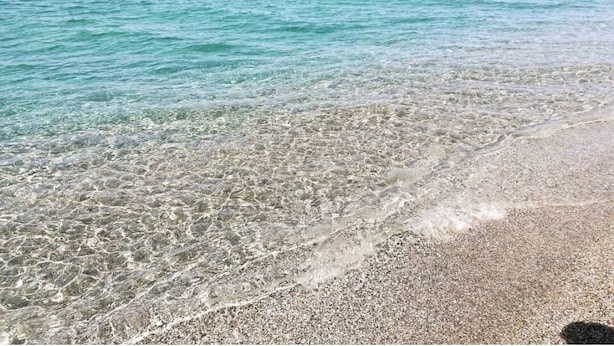 Una playa tranquila con aguas poco profundas y arena pedregosa.