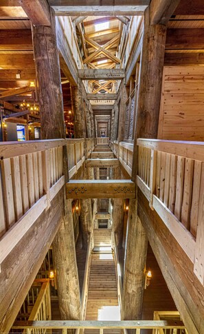 Un intérieur en bois avec un escalier central, bordé de rampes, qui mène à un niveau supérieur.
