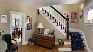 A staircase with a dark wooden handrail and white balusters, leading to a landing with a framed picture and a lamp.