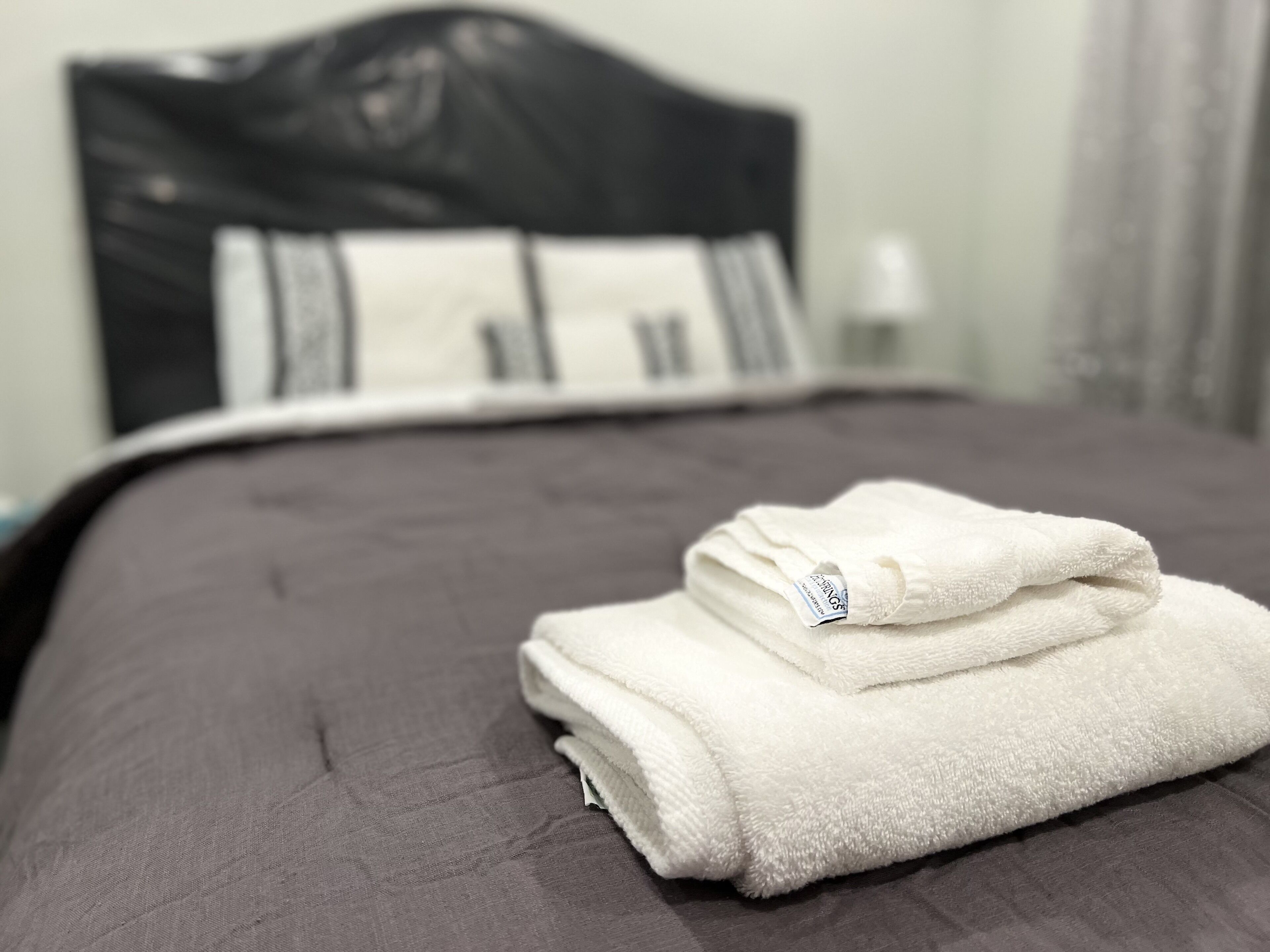 Un lit bien fait, avec une serviette blanche pliée posée sur le dessus.