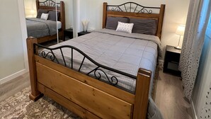 A bedroom with a wooden bed, a mirror, a nightstand, and a patterned rug. - LUXURIOUS 3 BR Home in CENTRAL Calgary b/W AIRPORT & Downtown  (Calgary)