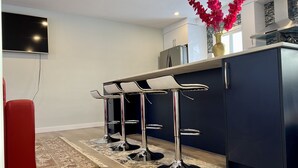 A modern kitchen with dark cabinetry, a built-in oven, and a flat-screen TV mounted on the wall. - LUXURIOUS 3 BR Home in CENTRAL Calgary b/W AIRPORT & Downtown  (Calgary)