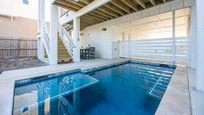 Ein Schwimmbecken mit Holzterrasse und überdachtem Bereich mit Treppe.