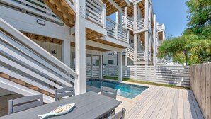 Ein Poolbereich mit Holzterrasse, Pool und Esstisch mit Stühlen.