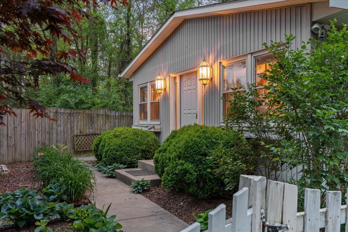 A residential house with a wooden fence, a pathway, and well-maintained bushes.