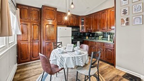 A kitchen with wooden cabinets, a dining table with chairs, and a refrigerator.