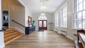A spacious hallway with wooden flooring, a grand staircase, and a large chandelier. - McKinley Mansion Full Building w/Bball gym, Arcades, 13000 sqft, Sleeps 70.  (Pocatello)